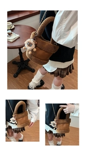 Détail du sac seau en peluche marron avec pendentif lion et chaîne dorée sur table