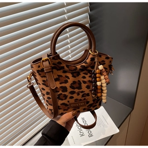 Detail view of leopard print bucket bag with round handles and colorful wood bead charm