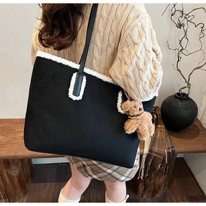 Dettaglio della borsa a spalla nera in peluche con ciondolo a orsetto e stile autunnale