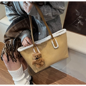 Dettaglio della borsa tote in camoscio giallo con bordo in lana bianca e ciondolo orso