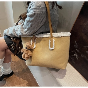 Dettaglio della borsa tote in peluche cammello con bordo in montone bianco e ciondolo orso