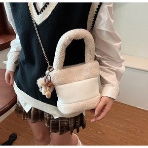 Détail du sac seau en peluche blanche avec patchwork en cuir et chaîne dorée