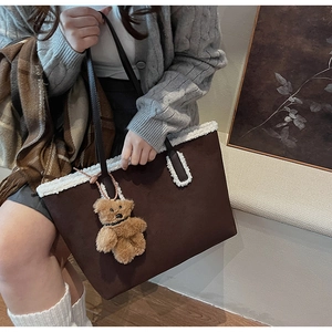 Dettaglio borsa tote in pelle scamosciata marrone con bordo in pelliccia sintetica bianca
