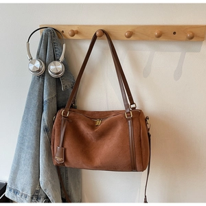 Detail of brown suede Boston bag with leather handles and gold-tone zipper hardware