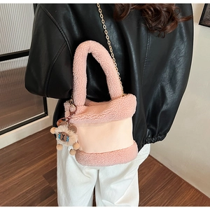 Détail d'un sac seau en peluche rose avec chaîne dorée et breloque mouton