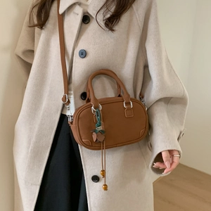 Close-up of brown matte leather handbag with flower pendant and silver buckle detail