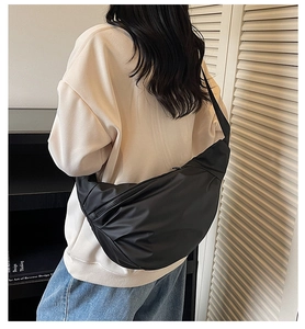 Minimalist black nylon crescent crossbody bag styled with casual outfit and book background