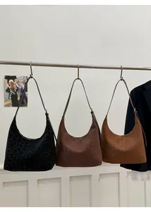Three leopard print tote bags in black, dark brown, and tan hanging on a metal bar