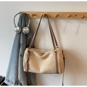 Detailed macro view of a beige suede Boston bag featuring dark brown leather trim and tag