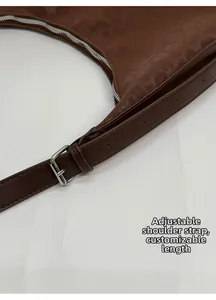 Detail view of the brown leather hobo bag showing the adjustable strap and silver buckle