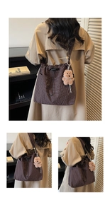 Detailed view of brown checkered canvas bag with cute plush bear pendant accessory