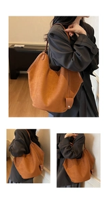 Detail shot of brown suede tote bag featuring metallic buckle charm and soft texture
