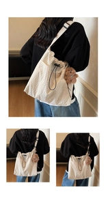 Detail of off-white pleated canvas bag featuring drawstring closure and teddy bear charm