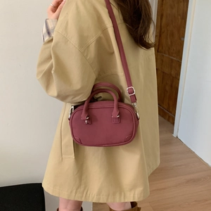Detail of burgundy crossbody bag featuring a matte finish and silver metal hardware