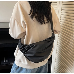 Fashionable black nylon crescent crossbody bag with pleated texture on model