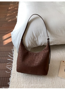 Detail of retro leopard print tote bag in dark brown suede on a textured carpet