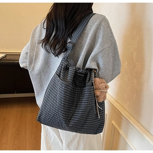 Detail of checkered canvas tote bag with adjustable strap and plush bear charm