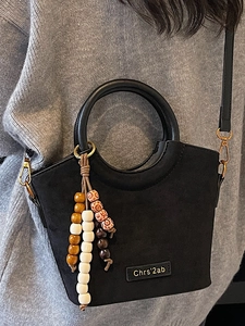 Chic black matte bucket handbag with round top handles and a colorful beaded tassel pendant