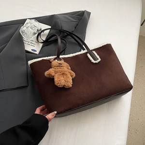 Dettaglio della borsa tote marrone scuro con bordo in ecopelliccia bianca e ciondolo