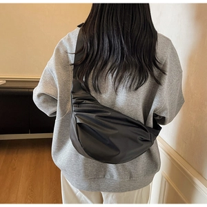 Detail view of stylish black nylon crescent crossbody bag with pleated texture on model