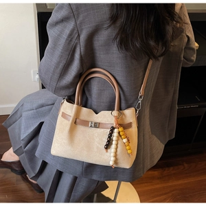 Detalle de un bolso de gamuza beige con correas marrones y cuentas de madera decorativas