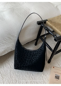 Close-up of leopard print hobo bag on white rug showing retro texture and silver zipper