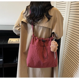 Detail of red checkered canvas tote with drawstring closure and cute plush bear charm