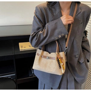 Detalle del bolso de ante beige con borla de cuentas de madera y cierre giratorio plateado