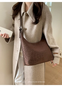 Close-up of a minimalist vintage hobo bag with dark leopard print and smooth texture