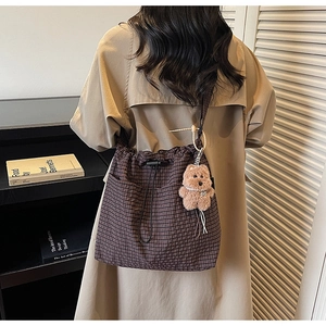 Detail of dark brown checkered canvas tote with drawstring and plush bear charm