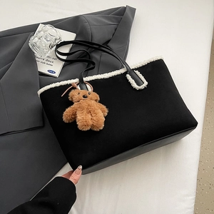 Dettaglio della borsa tote in pelle scamosciata nera con bordo in ecopelliccia e orsetto