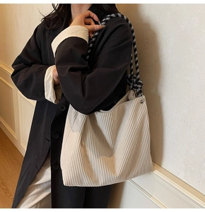 Detailed texture of corduroy tote bag with black and white plaid woven rope handle