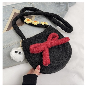 Détail du sac en peluche noir avec grand nœud rouge et fleurs sur la bandoulière