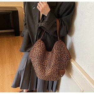Detailed view of spacious leopard print tote bag with brown leather handles worn over shoulder