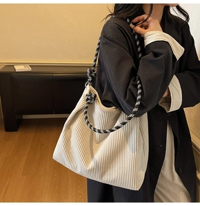 Detail of off-white corduroy tote bag showing large capacity and black-white checkered strap