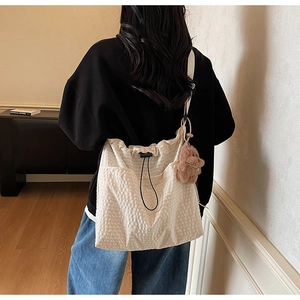 Detail of cream canvas tote bag with waffle texture, drawstring closure and bear charm