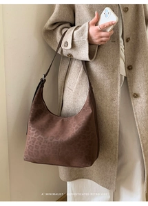 Close-up of leopard print hobo bag with adjustable brown leather strap on beige wool coat