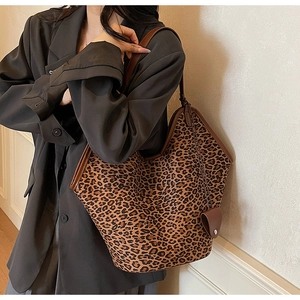 Detail of leopard print tote bag featuring brown leather trim and stylish hanging charm