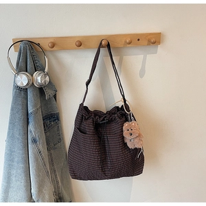 Detail of coffee plaid canvas bag featuring drawstring closure and a plush bear charm