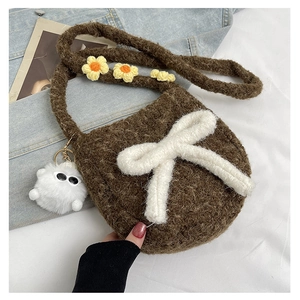 Détail du sac bandoulière en peluche marron avec un nœud blanc et un charm monstre poilu
