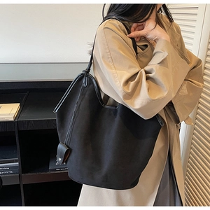 Detail of minimalist black suede tote bag with matte finish and smooth leather trim