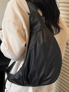 Minimalist black nylon crossbody dumpling bag with wide shoulder strap and brand label