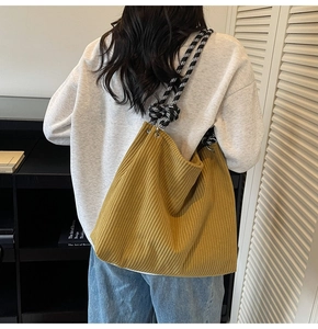 Detail view of mustard corduroy tote bag featuring a checkered braided wide shoulder strap