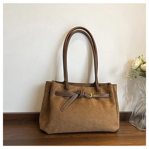 Dettaglio di una borsa tote in pelle scamosciata marrone con cinturino e fibbia in oro