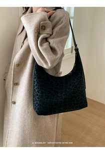 Minimalist hobo bag with vintage leopard pattern worn over a classic beige coat
