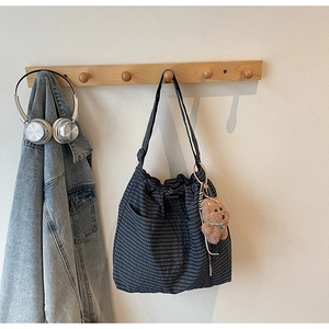 Detail of checkered canvas tote bag with side pockets and a cute plush bear charm