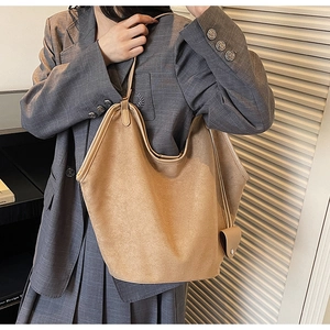 Detail of a large camel suede tote bag worn over the shoulder with a stylish blazer