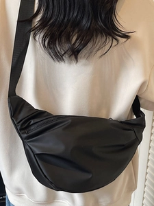 2025 trendy black nylon half-moon crossbody bag shown on model in minimalist style
