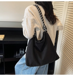 Detail of black corduroy tote bag with black and white checkered knot shoulder strap