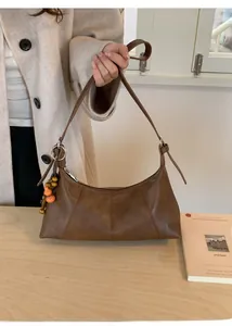 Detailansicht der braunen Vintage-Sichel-Tasche mit Anhängern aus Holzperlen und Kürbis